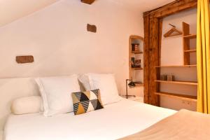 una camera da letto con un letto bianco con cuscini bianchi di Gite See You Soon - Studio Fun a Colmar