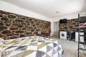 een slaapkamer met een stenen muur en een bed bij Casa da Avó Paraíso 1 in Machico