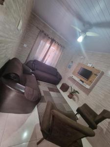 a living room with a couch and a tv at Casa com piscina em Bertioga 700m da praia in Bertioga +8 photos