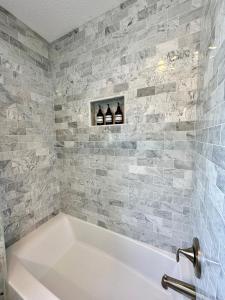 a white bath tub in a bathroom with gray tiles at Anna Maria Island Beach Front Condo - 50 steps to Beach in Holmes Beach +23 photos