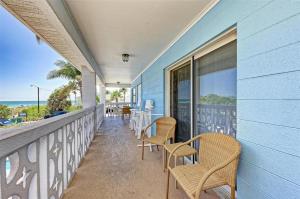 a balcony with chairs and tables on a blue building at Anna Maria Island Beach Front Condo - 50 steps to Beach in Holmes Beach