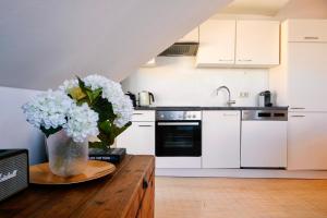 una cocina con armarios blancos y un jarrón de flores sobre una mesa en Helles und ruhiges Apartment im Zentrum, en Graz 13 fotos más