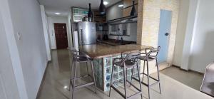 a kitchen with a counter with stools and a refrigerator at Apartamento Vista para Mar in Guriri