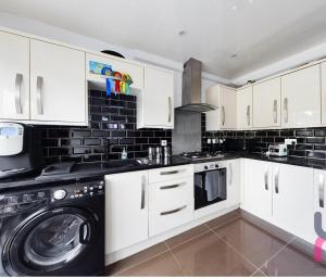 Una cocina con gabinetes blancos y lavadora y secadora. en house with hot tub, en West Derby
