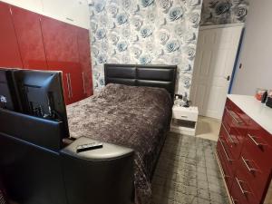 Un dormitorio con una cama y un escritorio con televisión. en house with hot tub, en West Derby