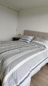 un grande letto in una camera bianca con finestra di Precioso departamento con vista a la playa a Papudo Altre 10 foto