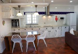 a kitchen with white cabinets and a table and chairs at Quinta da Padrela Vineyard House in Tabuaço