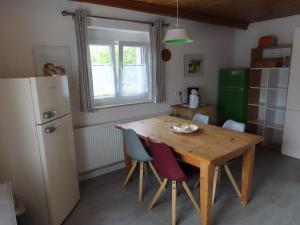 a kitchen with a wooden table and chairs and a refrigerator at Monteurwohnung bei Crailsheim Feuchtwangen in Fichtenau