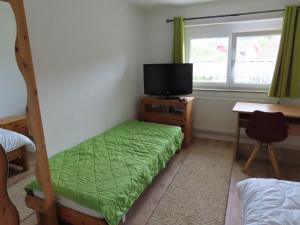 a bedroom with a bed and a tv and a desk at Monteurwohnung bei Crailsheim Feuchtwangen in Fichtenau