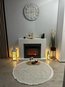 a living room with a fireplace with a clock on the wall at Landsberg Studio Apartment in Górowo Iławeckie +8 photos