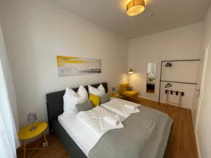 a bedroom with a bed with white sheets and yellow pillows at LS01 Deluxe Apartment, voll ausgestattet, zentral, groß in Magdeburg
