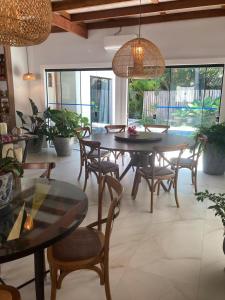a dining room with tables and chairs and windows at casa em Ihabela in Ilhabela
