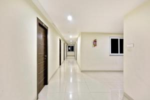 ハイデラバードにあるTownhouse Halcyon Deccan Inn Near Shilparamamの白壁と黒い扉の長い廊下