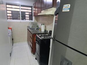 a small kitchen with a stove and a refrigerator at Ciudad Juan Bosch StoDgo este in La Javilla