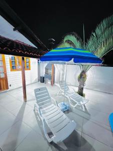 eine Gruppe von Stühlen und ein Sonnenschirm auf einer Terrasse in der Unterkunft Seu espaço em floripa! in Florianópolis