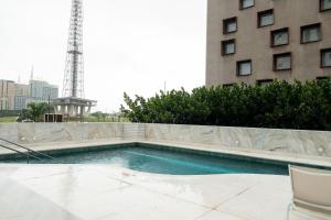 a swimming pool in front of a building with a tower at Flat moderno Hotel Mercure Líder in Brasilia