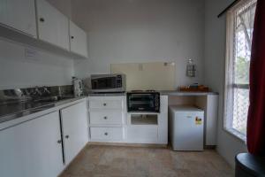 a small kitchen with white cabinets and a microwave at Casa Mexicana in Paeroa