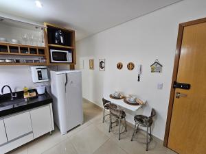 a kitchen with a white refrigerator and a table with chairs at Flat Lindíssimo de 2qts uma esquina do Flamboyant Shopping 206 in Goiânia
