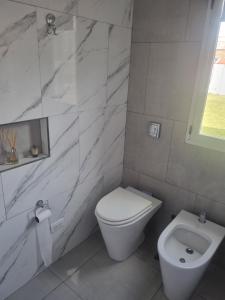 a white bathroom with a toilet and a sink at Tu descanso en Coronel Suarez in Coronel Suárez +14 photos