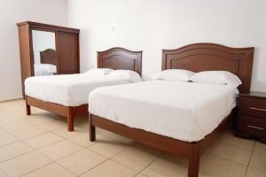 two beds in a bedroom with a mirror at Real Paraiso in Juticalpa