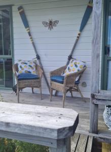 two wicker chairs and a spider on a porch at The Kraken Cottage in Whitianga +6 photos