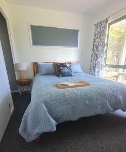 a bedroom with a bed with a book on it at The Kraken Cottage in Whitianga