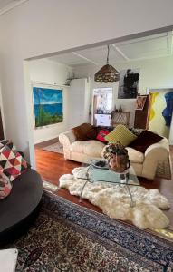 a living room with two couches and a table at Unique city bungalow in Whangarei +7 photos