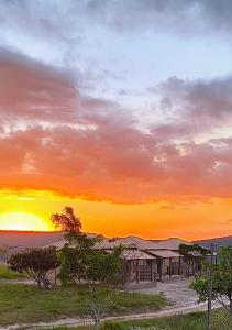 a sunset over a building in the desert at Chalé estrela do cruzeiro in São Thomé das Letras