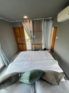 un dormitorio con una cama con dos almohadas. en นาน้าหมูฟาร์มสเตย์ NanamooFarmStay, en Trang