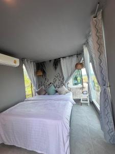 Un dormitorio con una cama blanca en una habitación. en นาน้าหมูฟาร์มสเตย์ NanamooFarmStay, en Trang