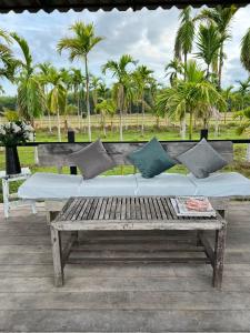 un banco de madera con almohadas en un patio con palmeras en นาน้าหมูฟาร์มสเตย์ NanamooFarmStay, en Trang