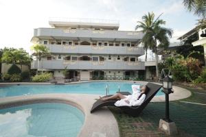 a woman sitting in a chair next to a swimming pool at Villa Isabel Hotel in Sorsogon