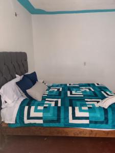 ein Bett mit einer blau-weißen Decke drauf in der Unterkunft Alma Andrea in San Cristóbal de las Casas