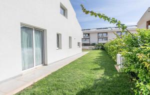 eine Außenansicht eines weißen Gebäudes mit einem grünen Hof in der Unterkunft Amazing Apartment In Marina Di Modica in Marina di Modica