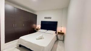 カリにあるApartamentos Sur de Cali Amplios bien ubicadosの白いベッドと茶色のキャビネットのある寝室