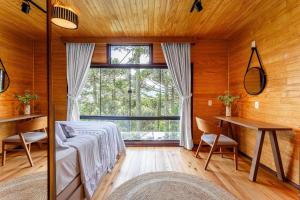 una camera da letto con un letto, un tavolo e una finestra di Chalé O Canto da Araponga a Águas Brancas