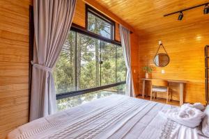 una camera da letto con un letto e una grande finestra di Chalé O Canto da Araponga a Águas Brancas