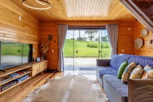 un soggiorno con un divano blu e una TV di Chalé O Canto da Araponga a Águas Brancas