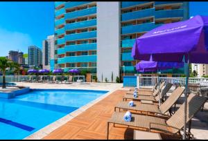 a pool with chairs and umbrellas next to a building at San Marino in Nova Iguaçu
