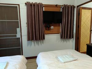 a bedroom with a bed and a flat screen tv at บ้านไร่ภูวังน้ำ in Ban Khlong Ki