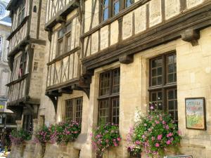 un edificio antiguo con flores en las ventanas en Logis Les Remparts, en Bayeux