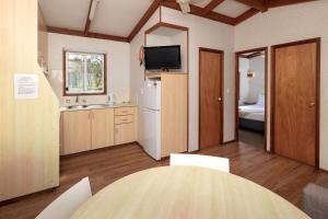 DurrasにあるBIG4 South Durras Holiday Parkのキッチン(テーブル付)、ベッドルーム(ベッド付)