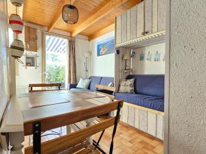 a living room with a table and a blue couch at Maisonnette proche plage et forêt, parking, wifi - FR-1-476-230 in La Faute-sur-Mer