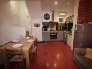 eine Küche mit einem Holztisch mit Stühlen und einem Kühlschrank in der Unterkunft Maison cosy 3 ch., proche marché et télécabine à Luchon - FR-1-313-237 in Luchon + 3 Fotos