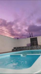 une piscine bleue avec un ciel nuageux en arrière-plan dans l'établissement mongaguá house 1 km, à Mongaguá