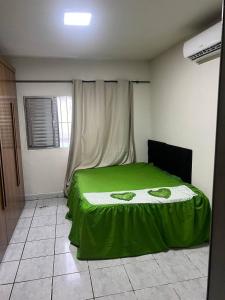 - une chambre avec un lit vert et une fenêtre dans l'établissement mongaguá house 1 km, à Mongaguá