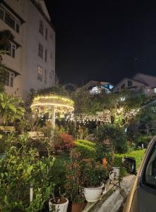 a garden with an umbrella and flowers in front of a building at Nhà Nâu Homestay DL- by BAY LUXURY in Da Lat