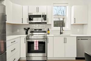 a kitchen with white cabinets and a stainless steel oven at Cozy Saanich Cottage ideal location to UVIC and Downtown in Victoria