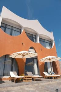 deux chaises et parasols devant un bâtiment dans l'établissement L'amant Boutiqué House Phú Quý, à Cu Lao Thu