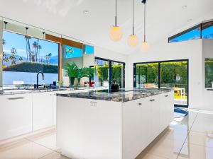 a kitchen with white cabinets and large windows at Villa Caliente in Palm Springs